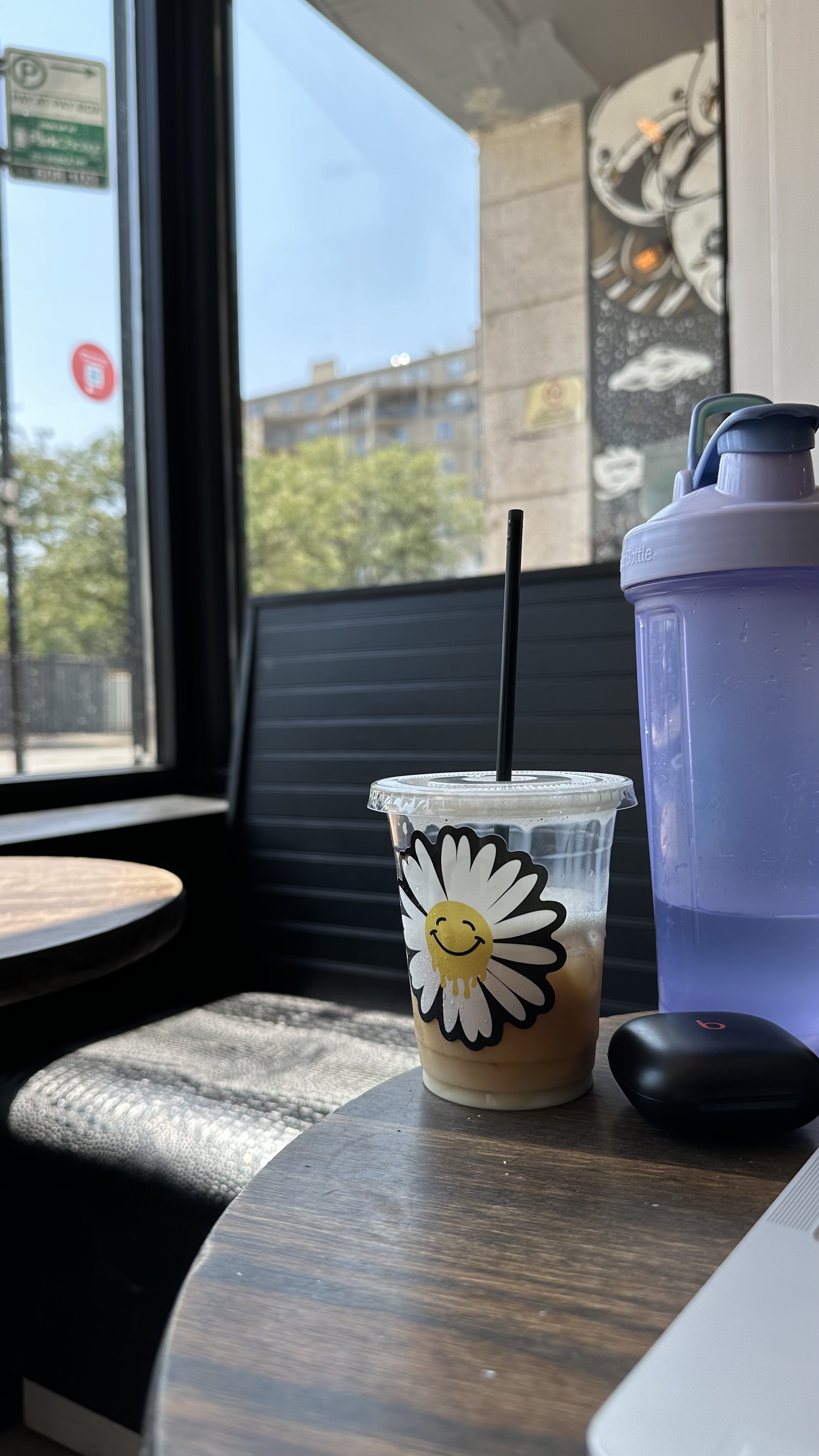 A cup with a flower sticker on a coffee shop table.